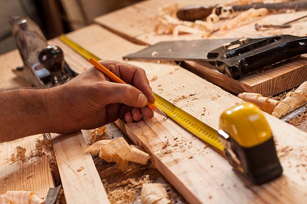 menuisier prenant des mesure sur une planche de bois venant d'être coupée