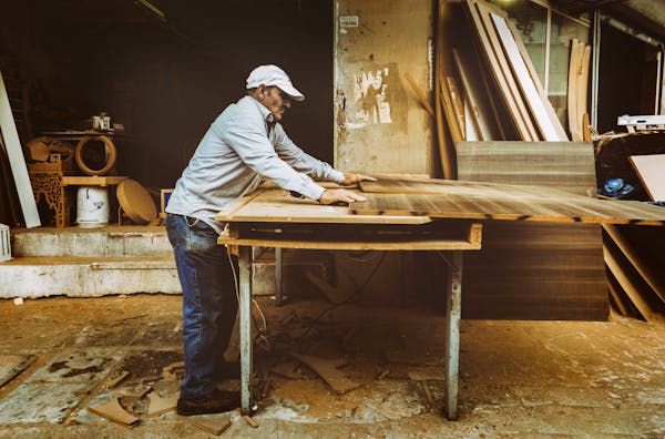 menuisier traditionnel coupant une planche en bois